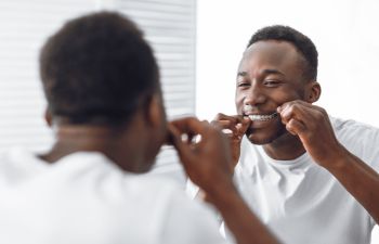 Afro american man flossing teeth
