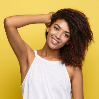 attractive young african american woman smiling and holding her hand on her head