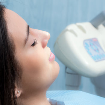 brunette with closed eyes lies in the dental chair