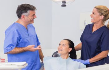 dentist and dental assistant advising woman patient on oral health