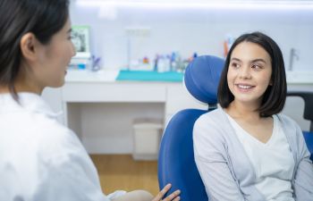 dentist consulting young woman sitting in dental chair