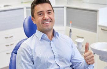 satisfied man shows thumbs up while sitting in the dentist chair