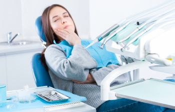 woman with dental pain sitting in dental chair before treatment