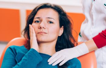 young woman with dental pain at dental office